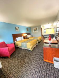 een hotelkamer met 2 bedden en een rode stoel bij Lakes Inn in Warsaw