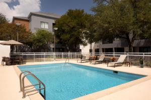 einen Pool mit Stühlen, einem Tisch und einem Gebäude in der Unterkunft Courtyard by Marriott- Austin Round Rock in Round Rock