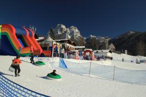 un groupe de personnes jouant dans la neige dans une station de ski dans l'établissement Hotel Garni Ongaro, à Selva di Cadore