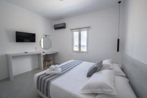 Habitación blanca con cama y escritorio en Kamara Sea View Villa en Kamari