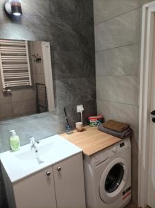 a bathroom with a washing machine and a sink at Apartament Zielone Tarasy in Rzeszów