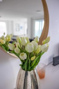 a vase filled with white flowers in front of a mirror at Seaview West Coast in Bournemouth