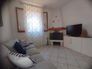 een woonkamer met een bank en een flatscreen-tv bij Il glicine Marina Romea in Marina Romea