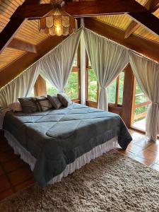 um quarto com uma cama com cortinas e um lustre em Casa das Pedras em Monte Verde