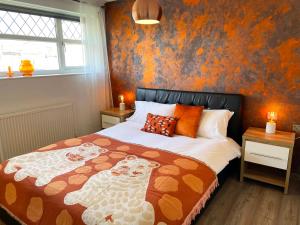 um quarto com uma cama com uma parede laranja em Bright, Airy & Beautifully Decorated 3 Bedroom Home em Kettering