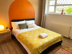 a bedroom with a large bed with an orange headboard at Bright, Airy & Beautifully Decorated 3 Bedroom Home in Kettering