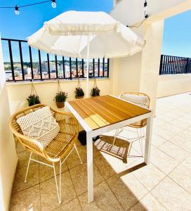 een tafel en stoelen op een balkon met een parasol bij Caparica Rooftop Beach Apartment in Costa da Caparica