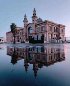 een groot gebouw met zijn reflectie in het water bij L'Incanto del Borgo Antico- Locazione Turistica in Bari