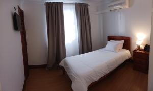a bedroom with a white bed and a window at Hotel Insular in Ponta Delgada