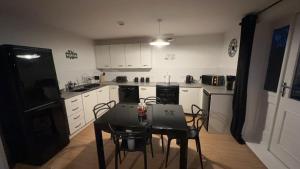 eine Küche mit einem Tisch und Stühlen sowie einem schwarzen Kühlschrank in der Unterkunft Waterfront town centre ipswich apartment in Ipswich