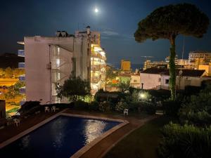 a swimming pool in front of a building at night at NICE APARTAMEN in Lloret de Mar