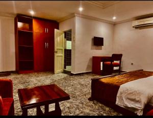a hotel room with a bed and a desk and a tv at E-Gold Luxury Hotel, Maitama in Abuja
