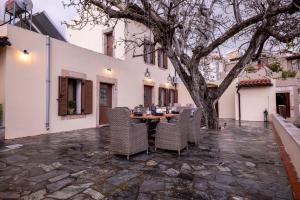 een patio met een tafel en stoelen en een boom bij WALNUT TREE VILLA in Archanes