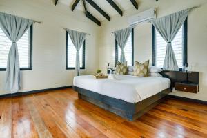 a bedroom with a large bed with wooden floors and windows at Shaka Caye All inclusive Resort in Belize City