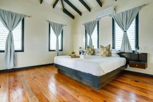 een slaapkamer met een groot bed, houten vloeren en ramen bij Shaka Caye All inclusive Resort in Belize City