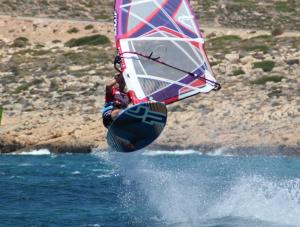 a person on a board with a sail on the water at LILIUM HOUSE PALEKASTRO in Palekastron
