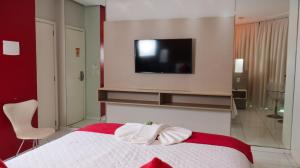 um quarto com uma cama e uma televisão na parede em Gênova Palace Hotel em Açailândia