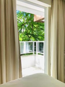 a bedroom with a window with a view of a tree at Tambaú Home Beira Mar - com varanda in João Pessoa