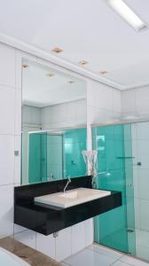 uma casa de banho com um lavatório e um espelho em Gênova Palace Hotel em Acailandia