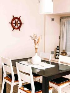 una mesa de comedor con sillas blancas y un jarrón con flores en Increíble casa frente al mar , planta baja en Torredembarra