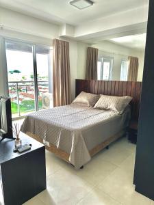 a bedroom with a bed and a large window at Flat Apartamento JK Duo in Sao Jose do Rio Preto