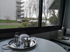 a table with a plate with tea pots and a window at La Charmille du Lac in Créteil
