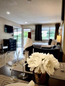una mesa con dos copas de vino y un jarrón con flores en Sheridan Suites Apartments en Dania Beach