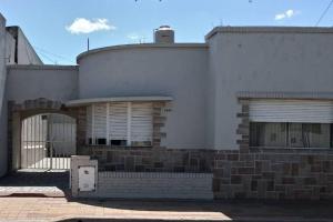 a white building with a gate and a building at Departamento al frente- Habitación con living in Tandil