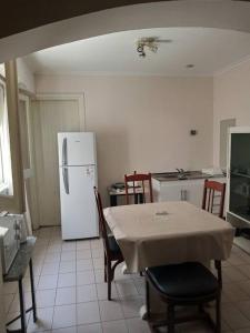 a kitchen with a table and a white refrigerator at Departamento al frente- Habitación con living in Tandil