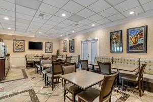 a dining room with tables and chairs and a tv at Best Western Plus Westbank in Harvey