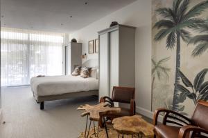 1 dormitorio con 1 cama y un mural de palmeras en Hôtel La Villa Juan Beach, en Juan-les-Pins