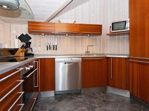 a kitchen with wooden cabinets and a stainless steel dishwasher at 8 person holiday home in Juelsminde in Sønderby
