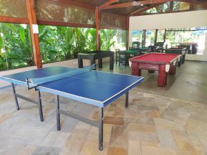 a ping pong table in a room with tables and chairs at Riviera Flat in Bertioga