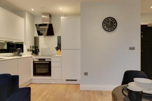 una cocina con armarios blancos y un reloj en la pared en New London Life Executive Apartments, en Chelmsford