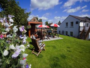 einen Garten mit Stühlen und Tischen sowie ein Gebäude in der Unterkunft Black Swan in Penrith