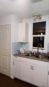 a kitchen with white cabinets and a sink and a window at Family and Pet friendly home in Cold Lake