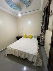 - une chambre avec un lit blanc et des oreillers jaunes dans l'établissement Cap Juby Apartment 1, à Tarfaya