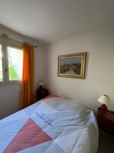 1 dormitorio con 1 cama y una pintura en la pared en Appartement Camargue Village, en Le Grau-du-Roi