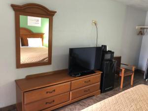 Dormitorio con tocador con TV y espejo en Hwy 59 Motel Laredo Medical Center, en Laredo