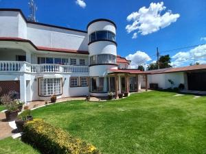 a large white house with a grass yard at Hotel La Aurora Like Home in Huamantla