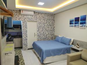 a bedroom with a blue bed and a kitchen at Riviera Flat in Bertioga