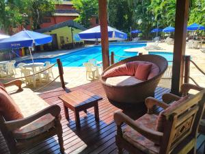 a deck with chairs and tables and a swimming pool at Riviera Flat in Bertioga
