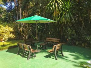 uma mesa de piquenique e bancos com um guarda-chuva verde em Riviera Flat em Bertioga