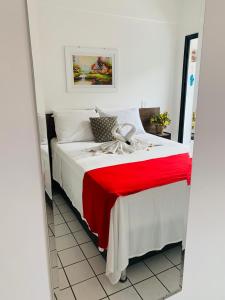 a bed with a red and white blanket on it at Apart. Praia da Costa Premium in Vila Velha