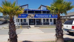 dos palmeras frente a un restaurante en Hostal LG Laraquete en Laraquete