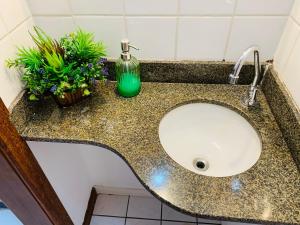 a bathroom sink with a green soap bottle and plants at Apart. Praia da Costa Premium in Vila Velha +35 photos