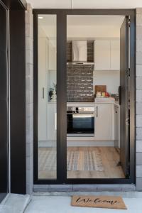 an open door to a kitchen with white cabinets at Grace Road Getaway in Tauranga