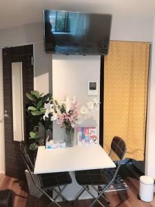 a white table with chairs and a tv on the wall at バラ苑目黒 目黒駅徒歩7分　恵比寿徒歩13分　静かな高級住宅　設備充実　花見名所 in Tokyo