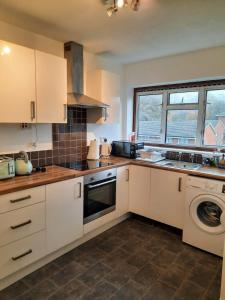 a kitchen with white cabinets and a sink and a dishwasher at Quality space in Havering atte Bower