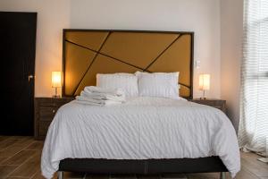 una habitación con una cama grande con sábanas y almohadas blancas en Rá Ngu, en Ixmiquilpan 33 fotos más